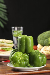Fresh Green Bell Peppers with Water Droplets on Kitchen Table