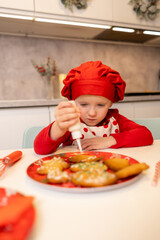 Young child decorates gingerbread cookies with icing in a kitchen during the holiday season
