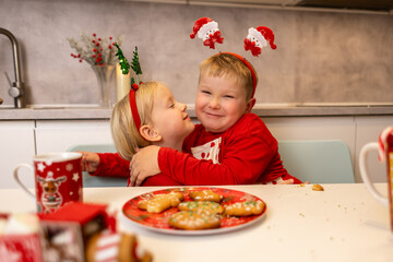 Children celebrate Christmas with cookies and festive hats in a cozy kitchen atmosphere