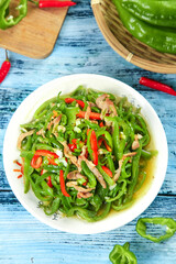 Stir-Fried Green Peppers with Pork in White Bowl - Fresh Chinese Vegetable Dish on Blue Wooden Background