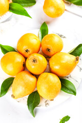 Fresh Loquat Fruits from Sichuan Panzhihua - Golden Asian Alpine Fruit with Green Leaves on White Marble Background