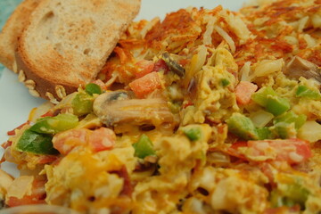Delicious american breakfast egg scramble with bacon veggies and wheat toast