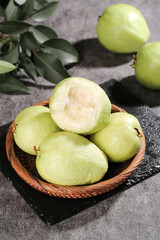 Fresh White Heart Guava Fruits from Guangxi China in Wooden Bowl with Tropical Leaves