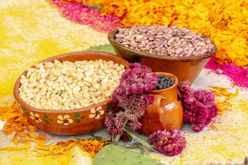 A table with three bowls of different colored food and flowers.Mexican Day of the Dead tradition, offerings, food, colors, decorations, and papel picado, La Catrina.