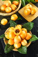 Fresh Loquat Fruits from Yunnan Mountains China in Woven Baskets with Green Leaves on Wooden Background