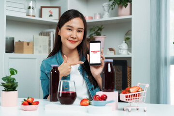 Smiling young beautiful Asian reviewing tasty mixed strawberry and cherry juice detox drinks,...