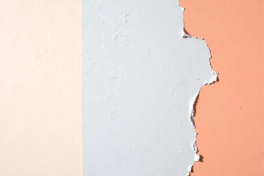 abstract texture of a wall with old, peeling paint layers revealing colors of beige, white, and peach during a home renovation - Powered by Adobe