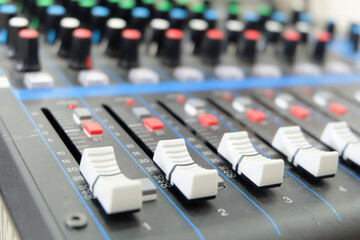 Obraz premium Close up of a Professional Audio Mixing Console with White Faders in Focus and Colorful Knobs Blurred in the Background