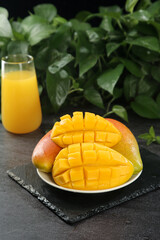 Fresh Ripe Mango Slices with Juice Glass and Green Plants Background