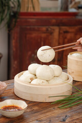 Handmade Fresh Pork Buns in Bamboo Steamer with Chopsticks and Scallion Garnish