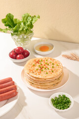 Handmade Buttered Scallion Pancakes with Fresh Vegetables and Sausages on White Kitchen Table