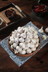 Fresh Shandong Farm Garlic Bulbs in Wicker Basket with Chinese Spices on Wooden Table