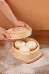 Fresh Handmade Dumplings in Traditional Bamboo Steamer Basket Being Opened by Hand