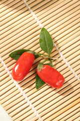 Red Goji Berries Wolfberries with Leaves on Bamboo Mat - Traditional Chinese Superfruit from Ningxia