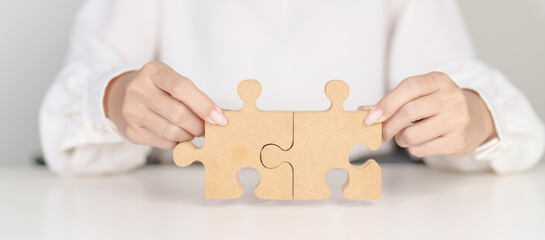 Woman connecting couple puzzle piece, wood jigsaw on table. Business solutions, mission, success,...