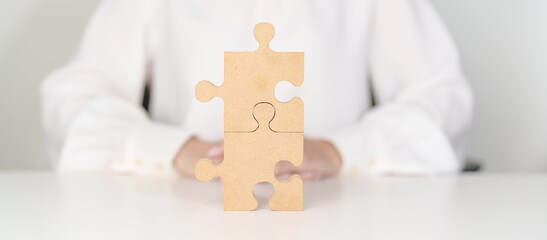 Woman connecting couple puzzle piece, wood jigsaw on table. Business solutions, mission, success,...