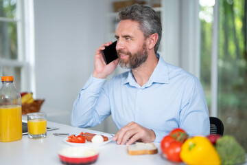 Man eats breakfast in the kitchen on a morning. A man enjoys fresh food at the kitchen table. A man eats cereal and fruit in the kitchen. Guy enjoys eggs and vegetables at the modern kitchen.