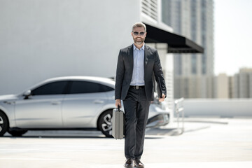 Successful businessman walk with with briefcase outdoors. Business man hold briefcase outside. Mature businessman in suit. Corporate business. Rich business man in suit. Outdoor business portrait.