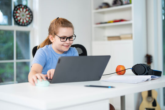 Kid preparing for exam with laptop. Student sitting at desk during distance education class. Smart child in virtual schoolwork and study. Child learning mathematics on laptop in home classroom.