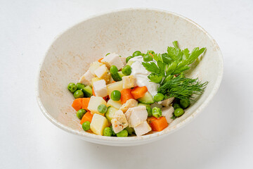 A vibrant mix of chicken, peas, carrots, and potatoes garnished with fresh herbs and yogurt
