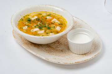 A cozy bowl of soup with tofu, colorful veggies, herbs, and a creamy dip