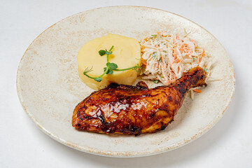 Grilled chicken leg with creamy mashed potatoes and crunchy herb-garnished coleslaw