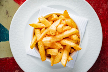 Golden, crispy fries are piled high in a white bowl, showcasing their tempting texture and color
