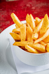 A bowl of golden, crispy fries sits invitingly on a bright red surface, ready to enjoy