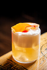 Sipping a delightful cocktail garnished with cherry and orange peel in an inviting bar atmosphere