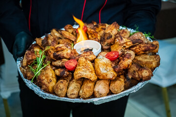 A joyful gathering with grilled chicken wings, sausages, and fresh greens on a vibrant platter