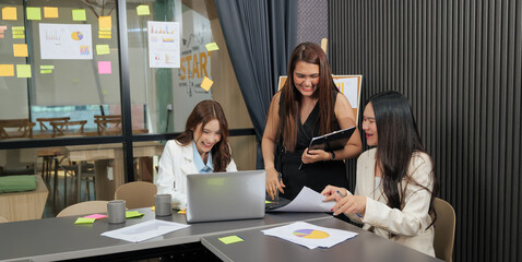 Business women meet, busy team people work on project, cheerful meeting discussing charts and financial data, sharing ideas in bright modern conference room