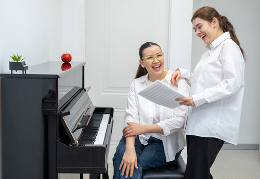 Two musicians young women sitting in a recording studio, holding music sheets and discussing their next song or score. - Powered by Adobe