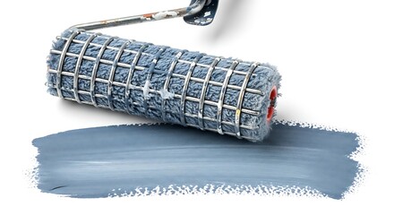 Close up of a paint roller with blue paint on a white background creating a textured stroke perfect for DIY and home renovation projects