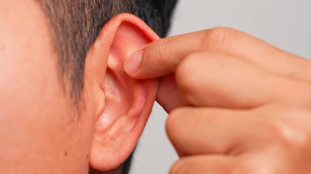 A close-up of fingers gently pulling and massaging the ear to stimulate alertness, highlighting relaxation, nerve activation, wellness, circulation, balance, clarity, and mindful self-care.
