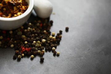 Variety of Peppercorns Spilled on Slate Surface with Bowl and Mortar