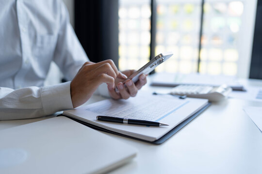 Businessman using smartphone for working in office room - Powered by Adobe