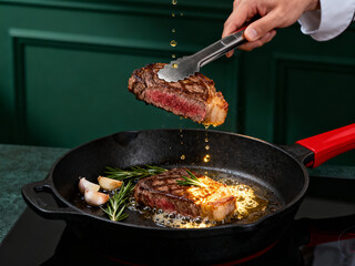 Chef Flipping Sizzling Medium-Rare Steak in Cast-Iron Pan with Garlic and Rosemary