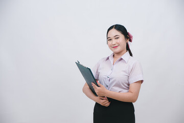 Young woman in a light purple blouse holding a clipboard with a welcoming smile in front of a plain background