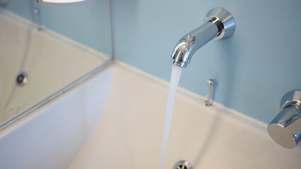 Modern bathroom faucet with running water in a clean space