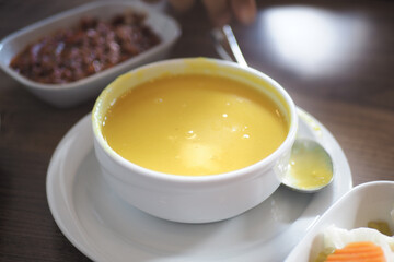 Yellow soup in a white bowl on the table