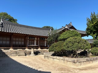 Traditional Korean houses and streets in Gyochon Village of Gyeongju, showcasing well-preserved hanok architecture, stone walls, courtyards, and a serene historic atmosphere under clear blue skies