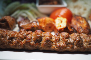 Grilled kebabs with sides served on a white plate