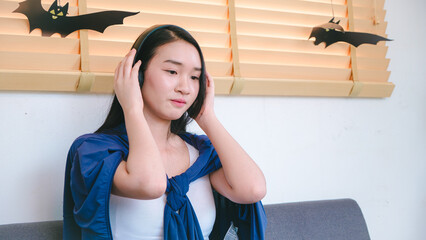 Young Woman Enjoying Music in a Cozy Indoor Setting with Halloween Decorations and Relaxed Atmosphere