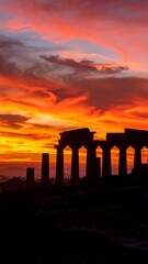 Ancient pillars silhouetted against a fiery sunset sky