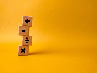 The image displays four wooden blocks with basic mathematical operation symbols on a yellow background