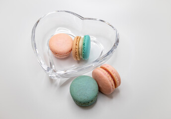 Macro studio shot of pink and blue green sweet macaron cookies in a crystal bowl, on white background with copy space