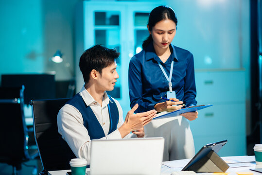 Asian colleagues discussing project plans and reviewing documents in a modern office. Concept of business teamwork, strategy - Powered by Adobe
