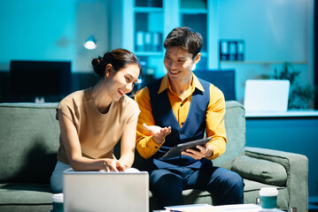 Asian couple working together with a tablet and laptop, discussing ideas with smiles. Concept of teamwork