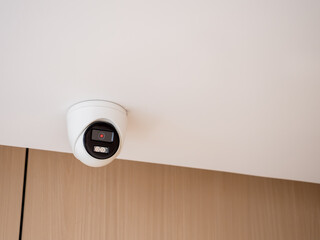 Indoor security camera mounted on ceiling in modern building, representing surveillance system,...