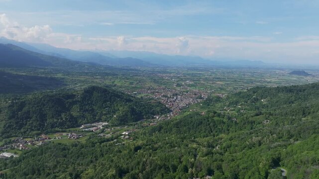 Bird&rsquo;s eye aerial view of a mountain village surrounded by hills and greenery, showing homes, huts and localized community depicting peaceful rural life amidst scenic nature.